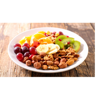 Bunter Obstteller mit Trauben, Bananen, Kiwi, Orangen und Nüssen auf einem Holzuntergrund.